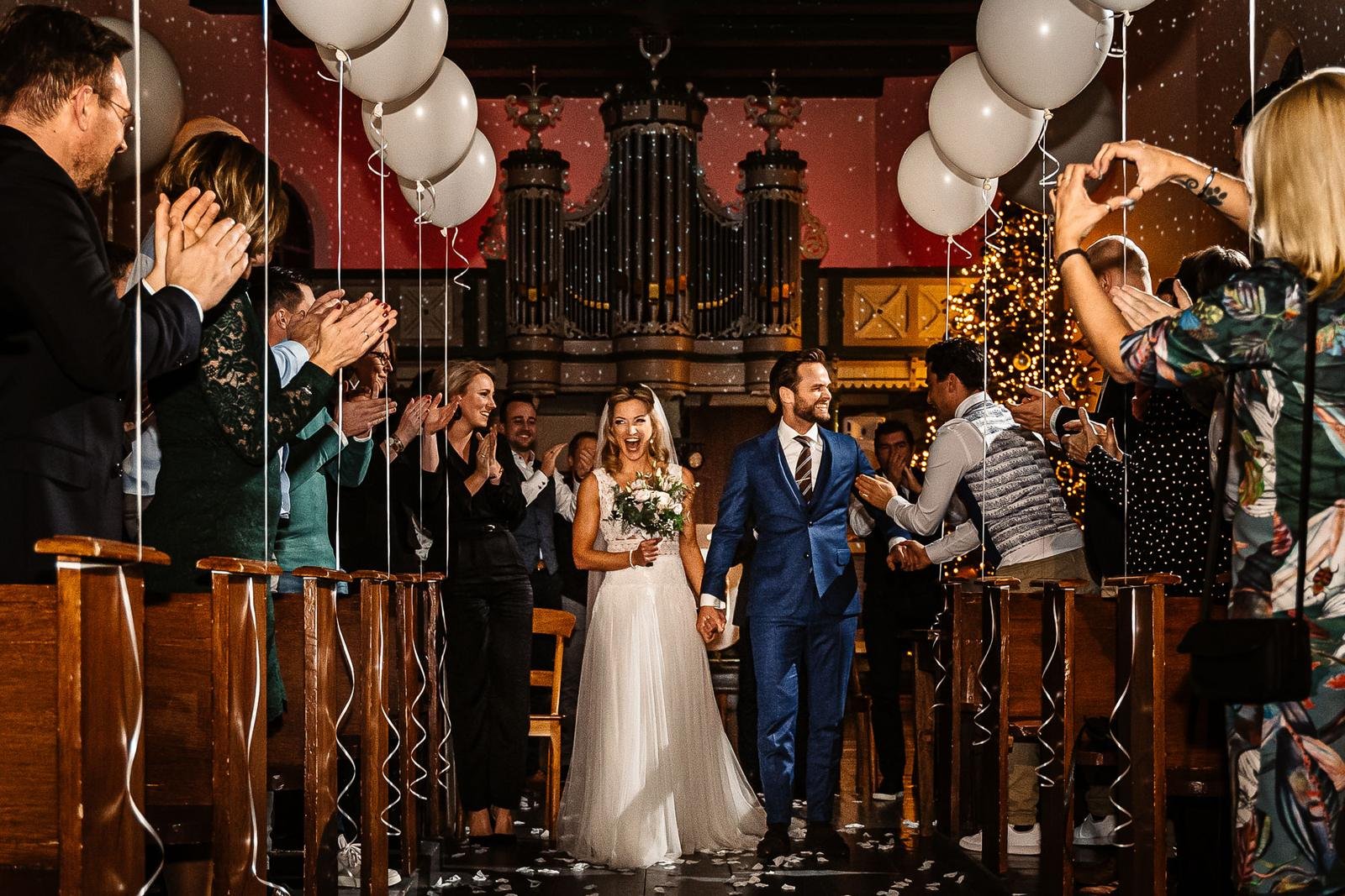 Bruidspaar verlaat de kerk van De Amshoff tussen de ballonnen en de confetti