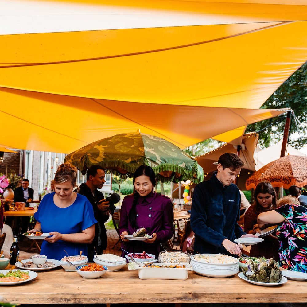 Bruiloftsdiner aan lange tafels onder de partytent