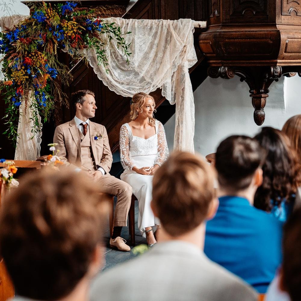 Huwelijksceremonie onder een bloemenboog in de kerk van De Amshoff