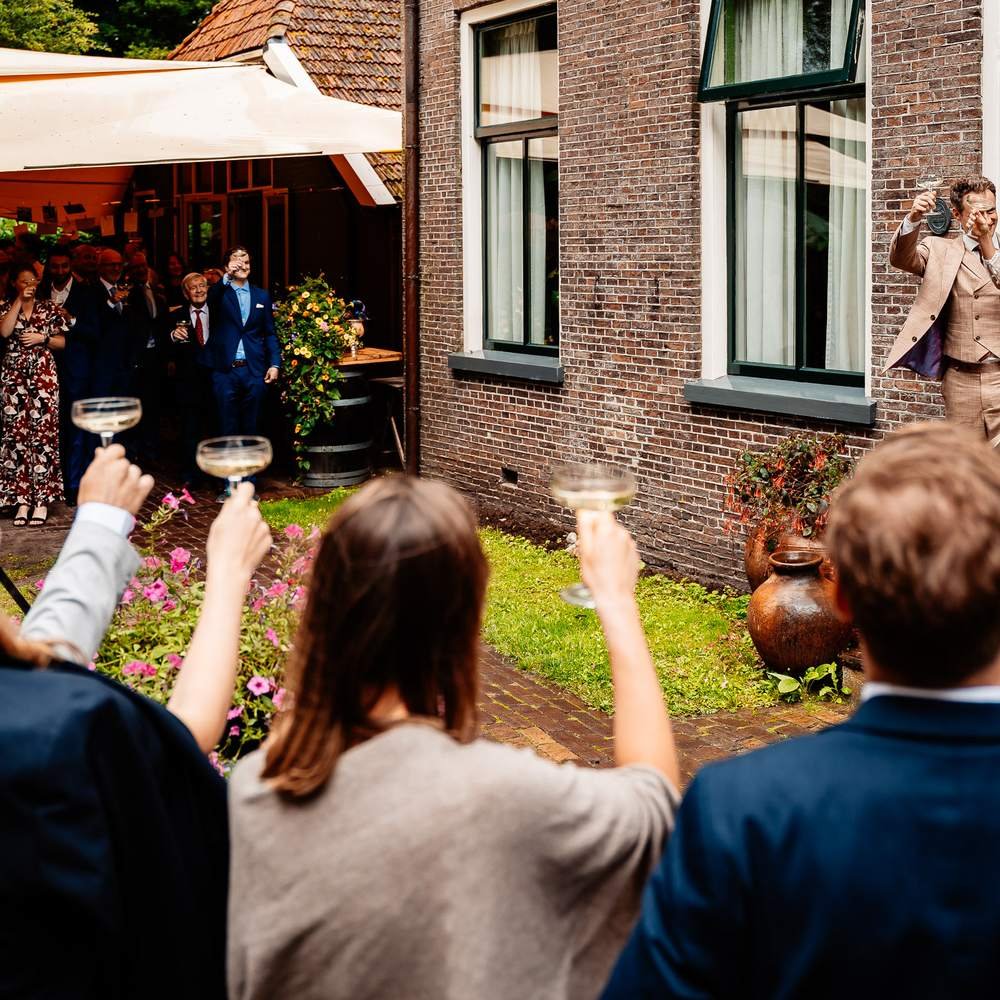 Gasten toosten op het bruidspaar in de tuin van De Amshoff